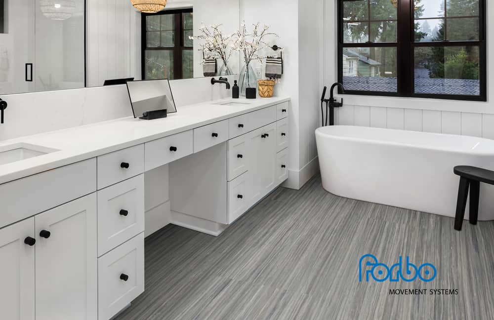 marmomarmopage Modern bathroom with gray waterproof flooring, white cabinetry, and a bathtub, showcasing premium flooring solutions.