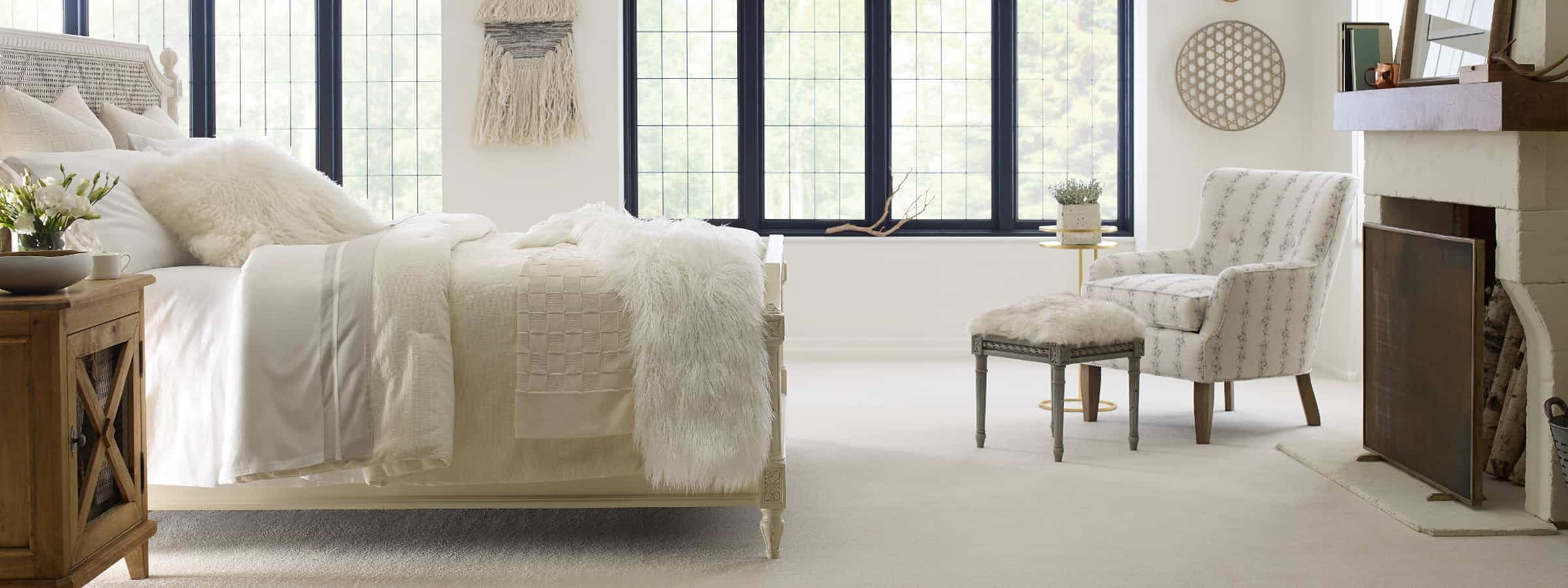 Luxurious bedroom with plush white bedding, hardwood flooring, and cozy seating area, showcasing quality flooring solutions from Dallas Watson Flooring.