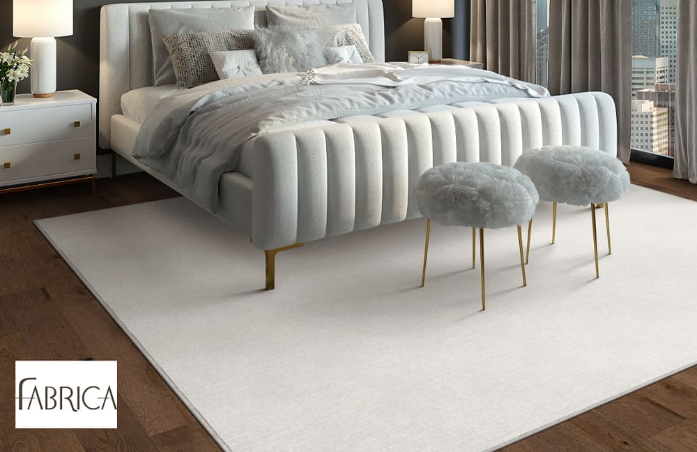 Luxurious bedroom with modern white upholstered bed and plush ottomans on a clean white flooring.