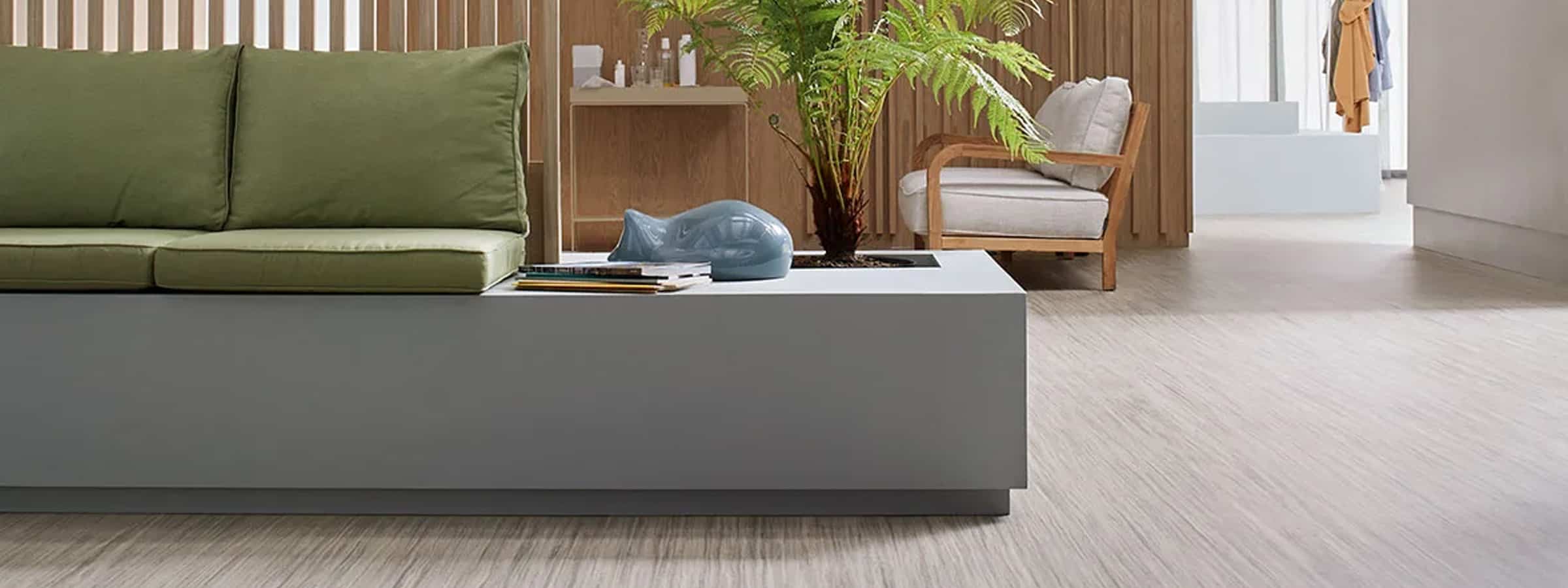 Luxury hardwood flooring in modern living room with natural wood accents and green sofa.