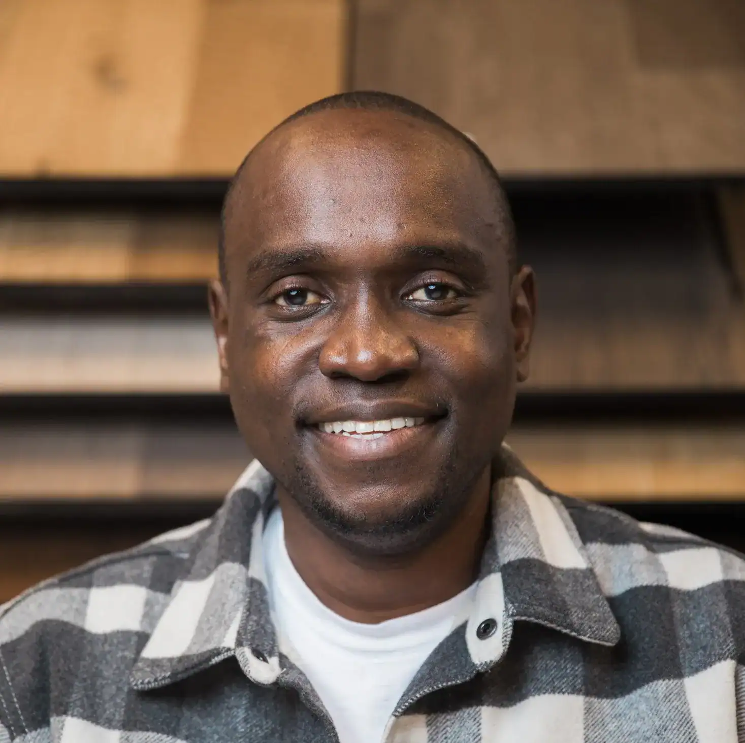 Professional man smiling, wood flooring background, interior flooring expert.