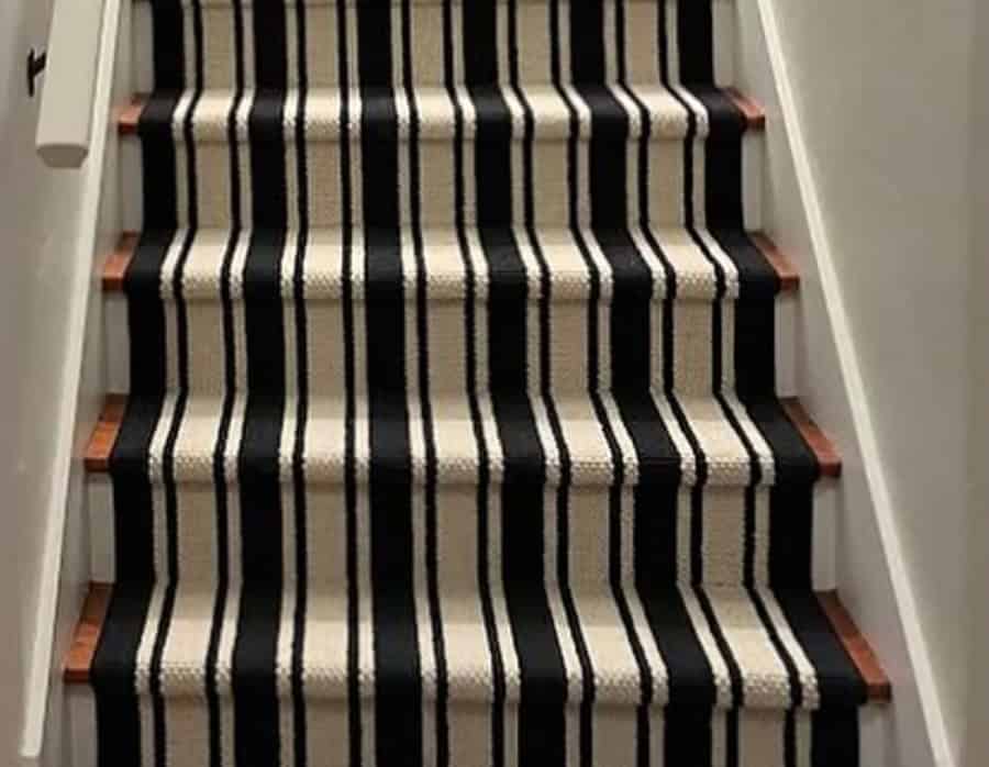Black and white striped stair carpet runner with hardwood edges.